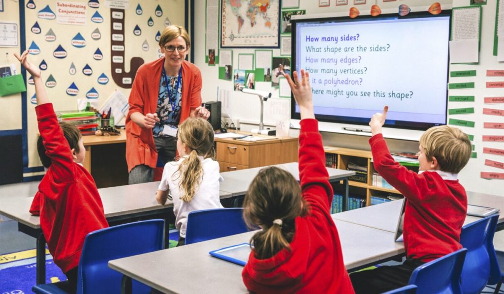 Classroom of children with their hands in the air