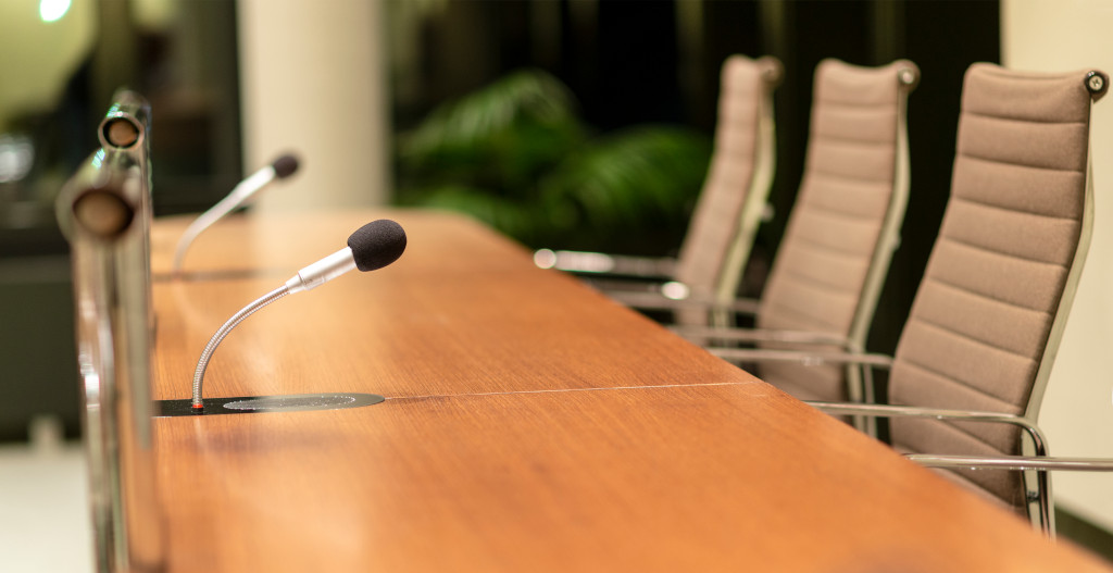 A boardroom with tables, chairs and microphones.