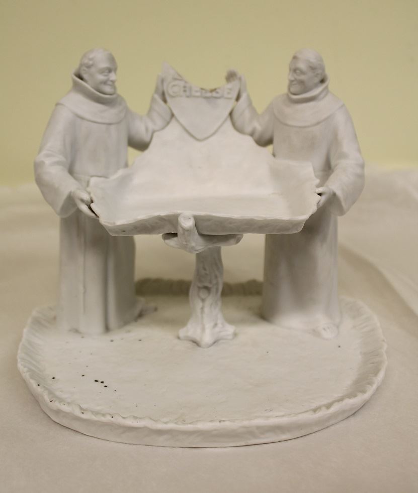 A ceramic dish held up by two monks