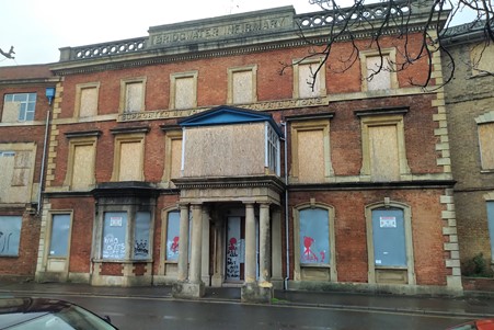 Image of the front of the old Bridgwater Hospital, brick fronted building with boarded up windows
