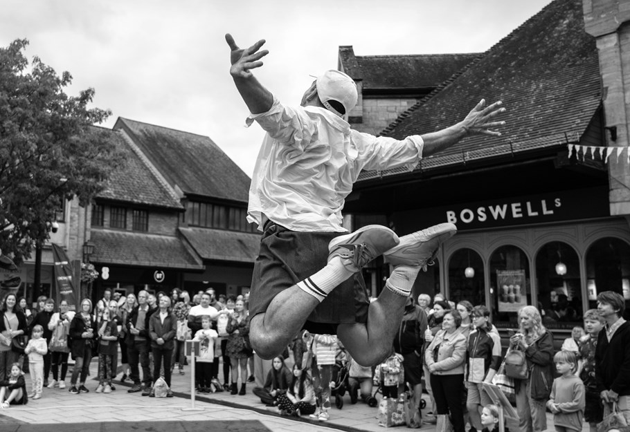 A street performer jumping in front a crowd.