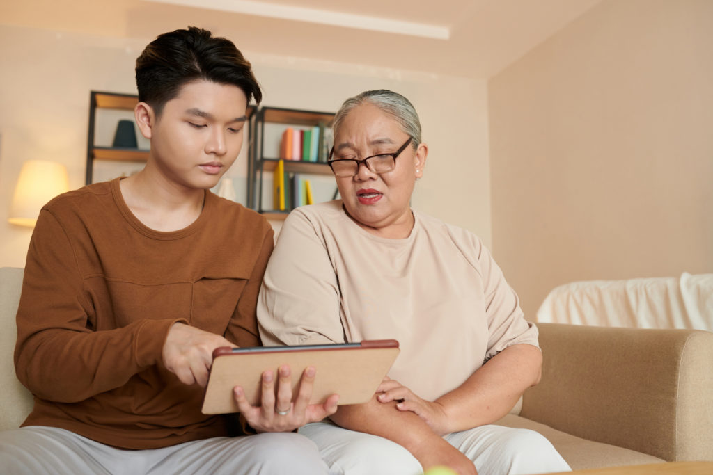 Man and woman sat on sofa looking at a tablet device.