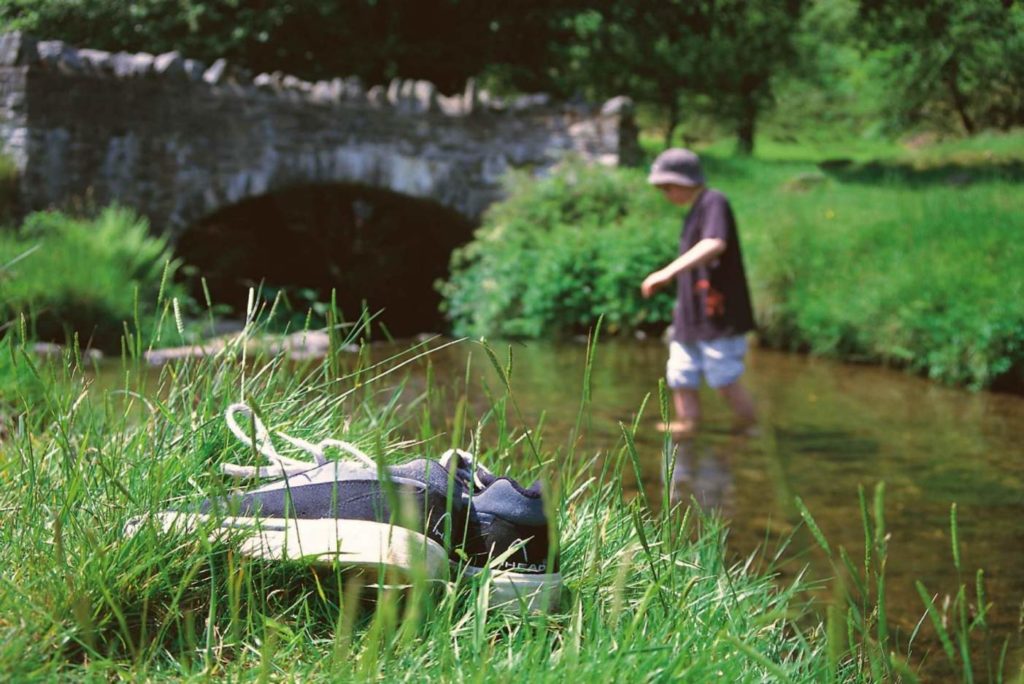 A young person paddling in river on a sunny day.