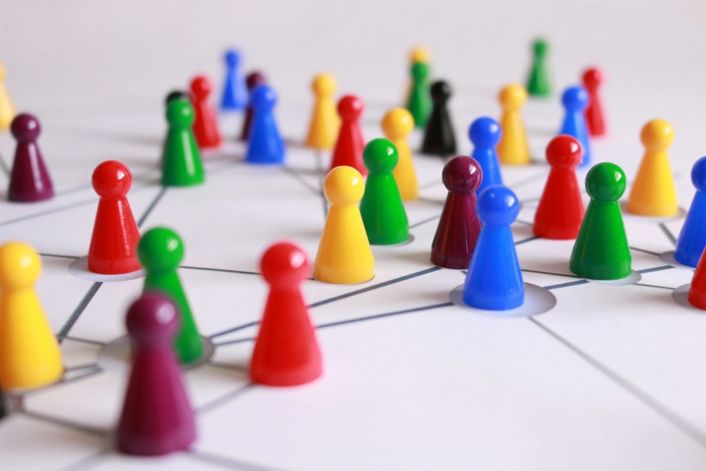 A network of multi-coloured ludo playing pieces on a white-lined surface.