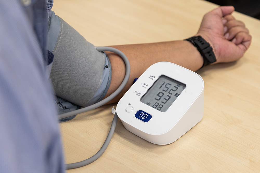 A blood pressure monitoring kit being used on a person's arm, showing hypertension with high systolic and diastolic readings.