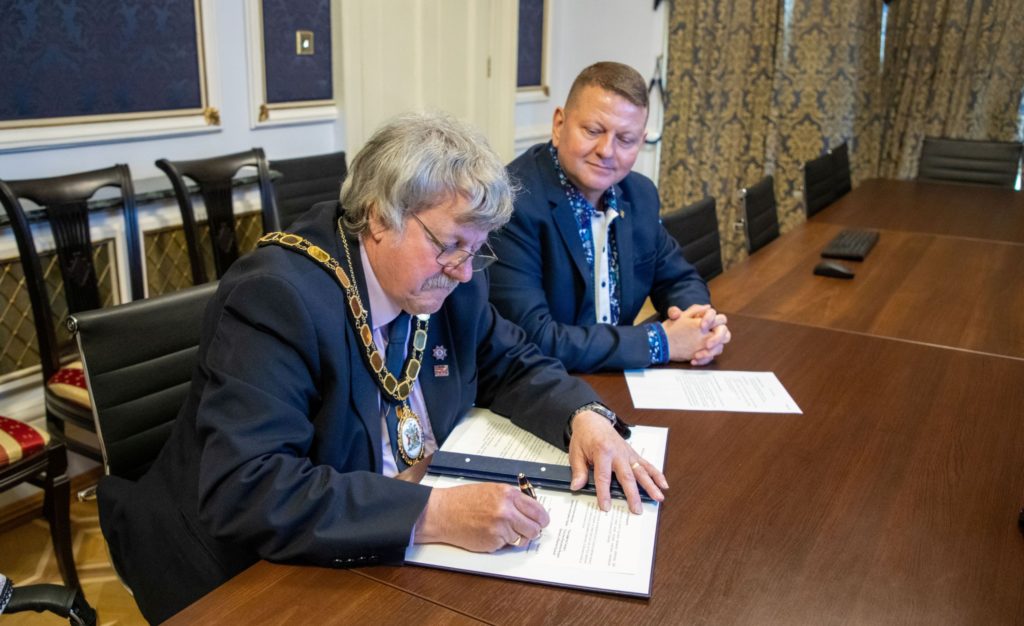 chair of Somerset Council Mike Best signs the agreement with Ukraine, watched by the Ukraine Ambassador