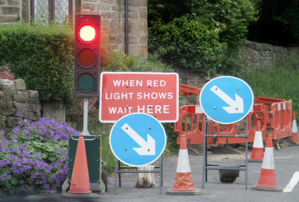 Roadworks with temporary traffic lights in rural village.