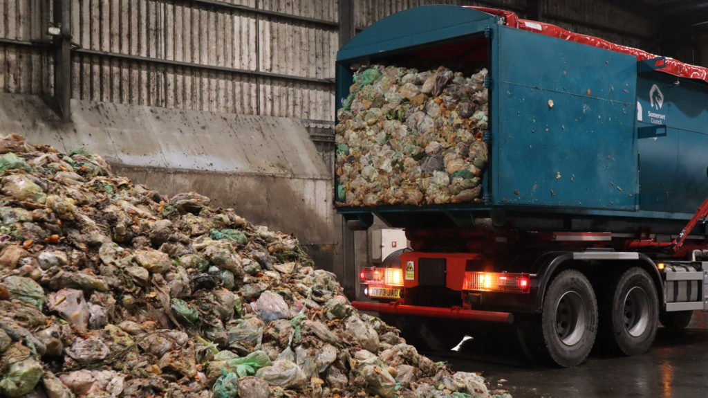 A lorry from Somerset Council unloads food waste for recycling at an indoor facility.