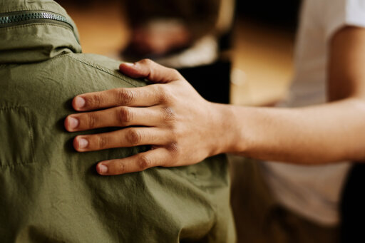 Hand is positioned supportively on a man's back.