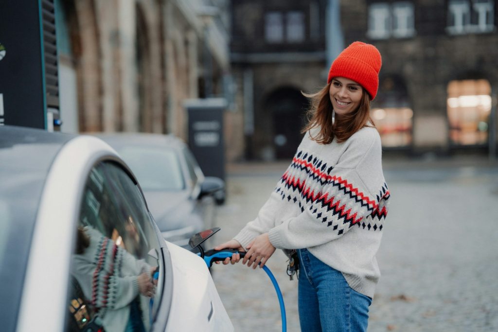 Woman plugging in a charging cable to an electric car