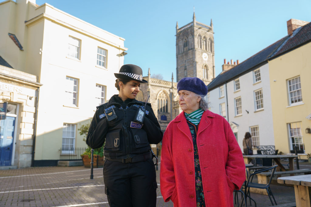 A woman and police officer walking through a high street.