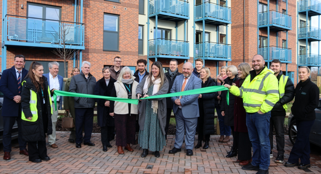 A ribbon-cutting ceremony marking the completion of new eco homes in Minehead, with officials gathered in front of the housing development.