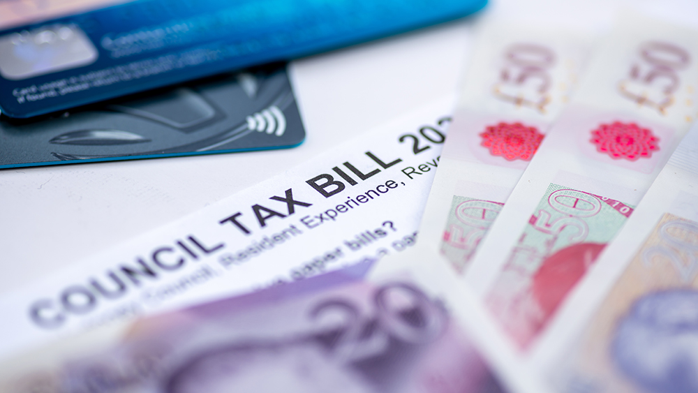 A Council Tax Bill in between Pound Sterling bank notes and bank payment cards.