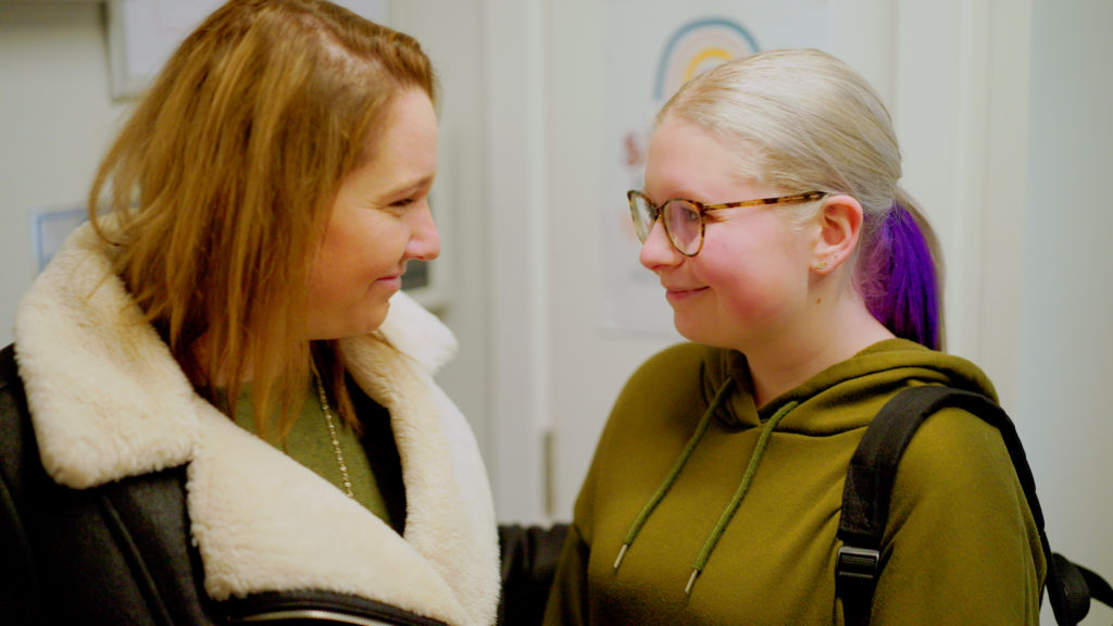 A woman and teenage girl smiling at each other