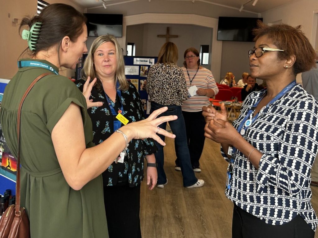 Three professional women are in discussion at an event.