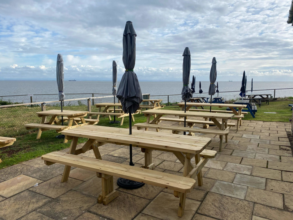 Picnic tables outside on a patio in a larger garden