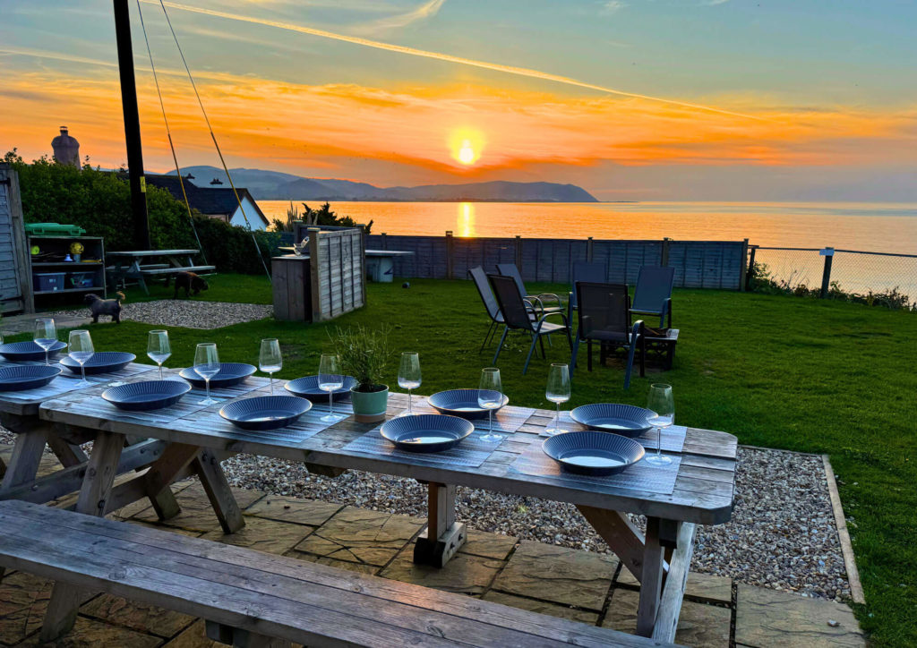 sunset over the coastline with a picnic table laid out with plates