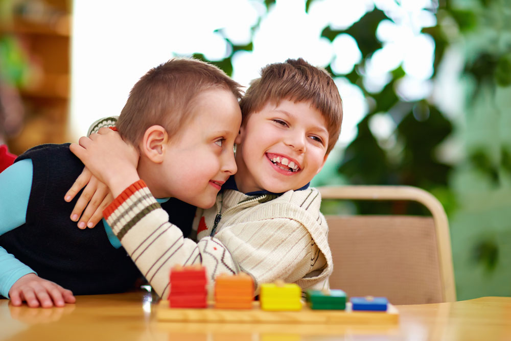 Two little boys playing with blocks and hugging