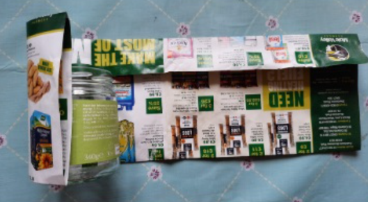 Folded newspaper being rolled around an empty jar