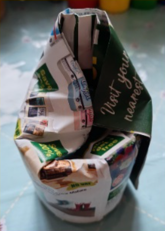 Newspaper rolled around a jar and folded over the top of the jar to form the base of the plant pot
