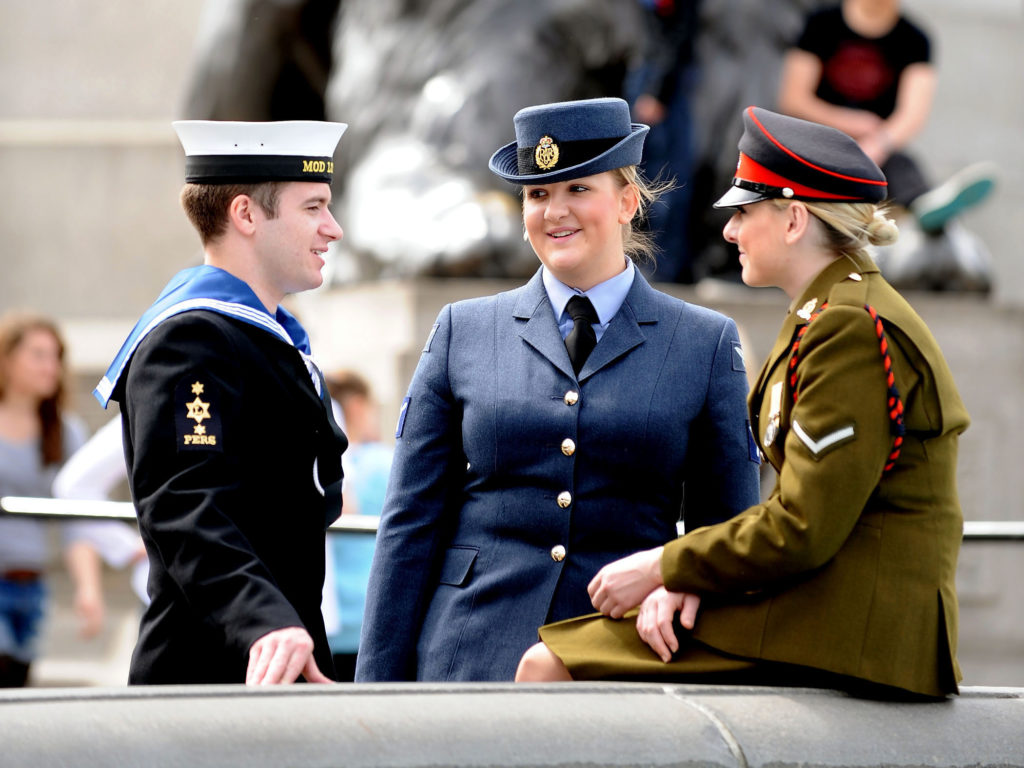 Three UK service members chatting beside a fountain, with a large lion statue in the background, ©UK MOD Crown Copyright.