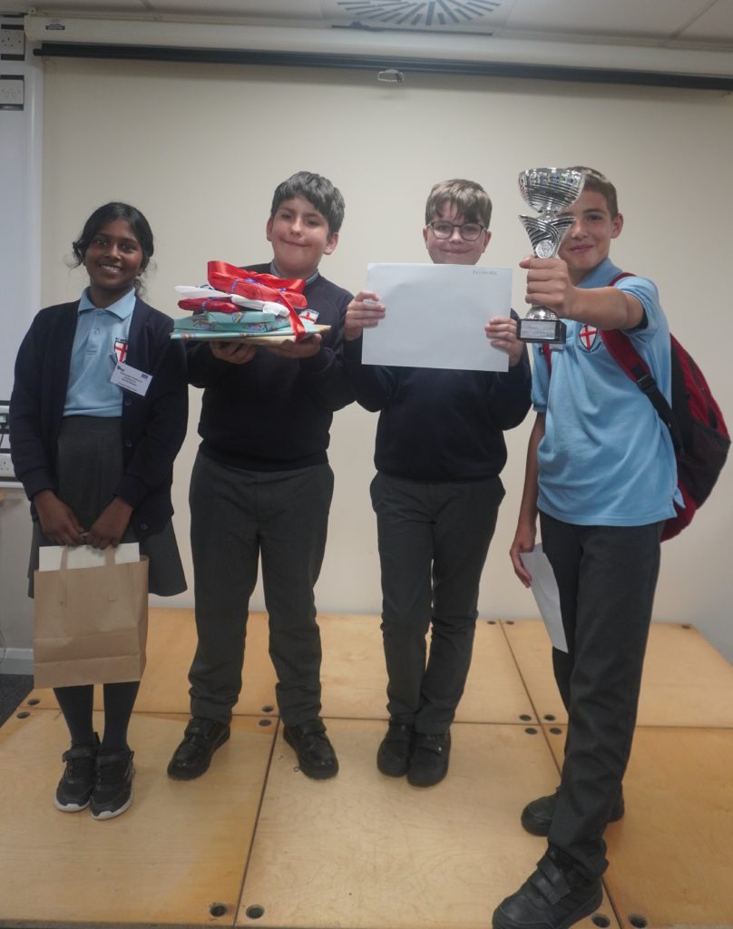 Four pupils from St George’s Catholic Primary School hold a trophy, certificate and prizes after children’s parliament event.