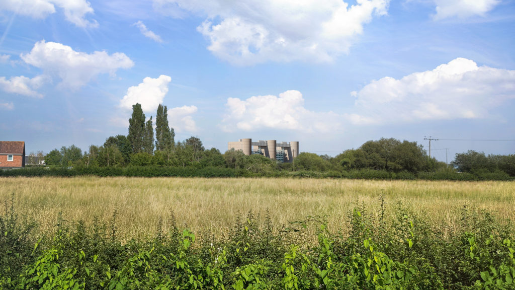 The barrier seen from a nearby field. It is visible above the tree line.