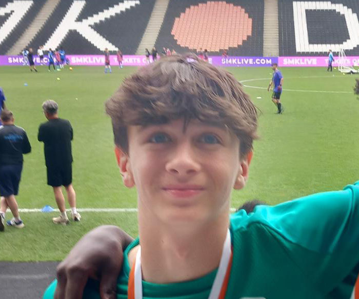 Lewis, wearing a Somerset Council football shirt and medal, stands pitchside at MK Dons Stadium after the national tournament.
