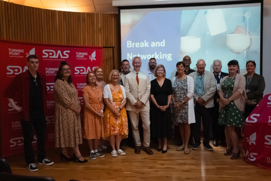 Graduates and supporters gather on stage at the SDAS Peer Mentor Programme celebration event in Taunton.