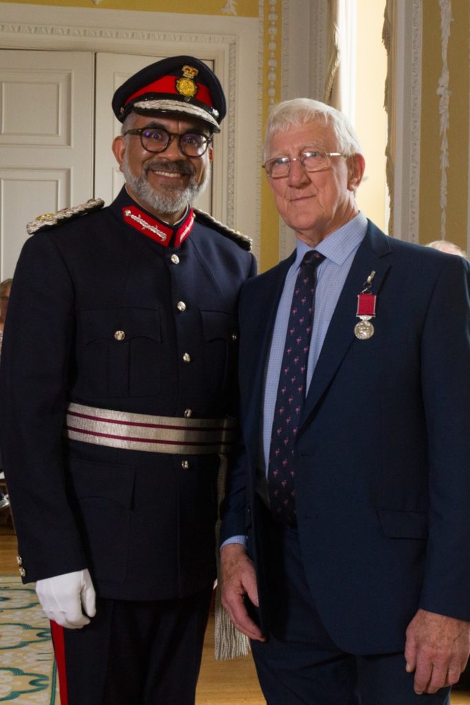 Eric Norman receives the British Empire Medal from Mohammed Saddiq, Lord-Lieutenant of Somerset, at an award ceremony.
