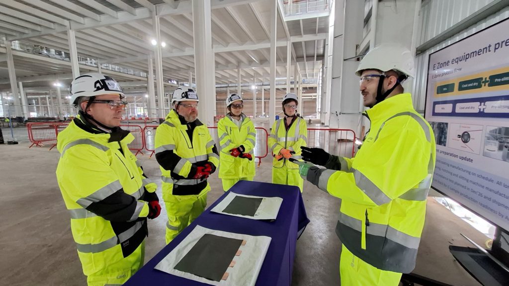 People in yellow high visibility clothing visit battery factory
